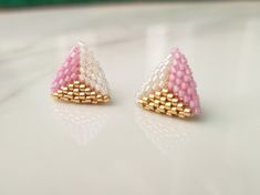 two small pink and white earrings sitting on top of a table next to each other