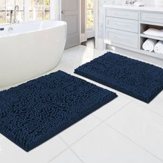 two bathroom rugs on the floor in front of a bathtub