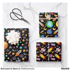 an assortment of space themed gift wrappers and scissors on a marble surface with the title, astronaut in space by yoliantionary