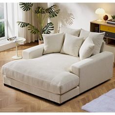 a large white couch sitting in a living room next to a lamp and potted plant