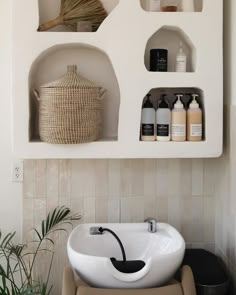 a white sink sitting under a shelf next to a potted plant in a bathroom