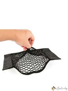 a hand is holding a black mesh bag on a white surface with the bottom half open