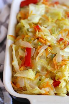 a casserole dish filled with cabbage, carrots, and other toppings