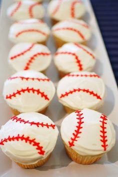 cupcakes with white frosting and red stitches are arranged in a row on a table