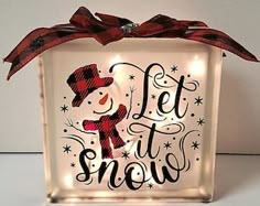 a lighted box with the words let it snow and a snowman wearing a hat