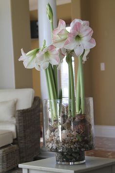 flowers in a vase on a table with rocks and gravel inside the vase, near a couch