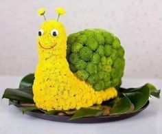 a yellow snail sitting on top of broccoli