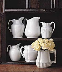 white vases with flowers in them are sitting on a shelf