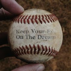 a person holding a baseball with the words keep your eye on the dream written on it