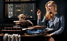 a woman sitting at a table with books and a skull in front of the window