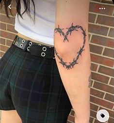 a woman with a heart tattoo on her arm and barbed wire in the shape of a heart