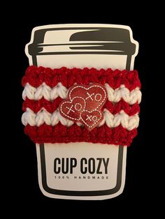 a cup cozy with a red and white crochet heart on it's side