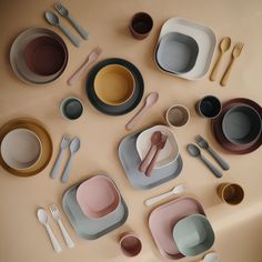 an assortment of dishes and utensils are arranged on a table top with beige walls