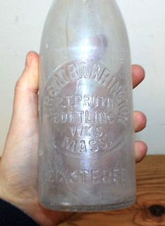 a person is holding a large glass bottle