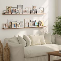 a living room filled with white furniture and pictures on the wall above it's couch