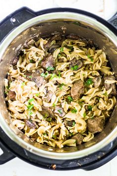 an overhead shot of pasta with mushrooms and parsley in a pot on the stove