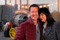 a man and woman standing next to each other in front of barrels with lights on them