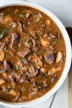 a white bowl filled with meat and mushroom stew