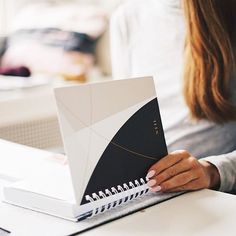 a woman sitting at a table with a notebook in front of her and looking at the screen