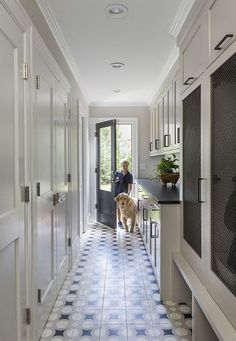 a woman and her dog are standing in the hallway between the kitchen and living room