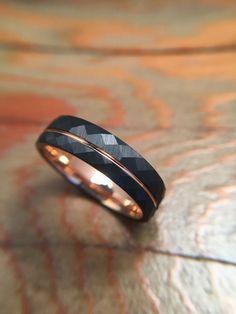 a black and gold wedding band on top of a wooden table