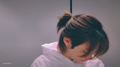 a woman with her hair in a bun wearing a white hoodie and looking down