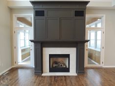 an empty living room with a fireplace in the center and wood floors on both sides