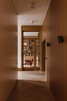 an empty hallway with wooden walls and doors leading to the dining room, which also has wood flooring