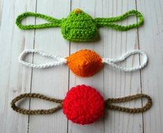 three crocheted toys are sitting on a white wooden surface, one is orange and the other is green