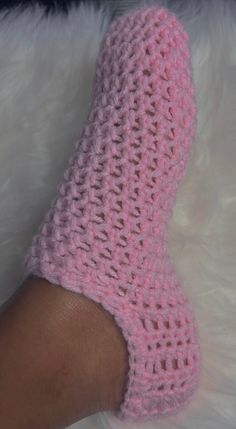 a woman's foot wearing pink crochet socks on top of white fur