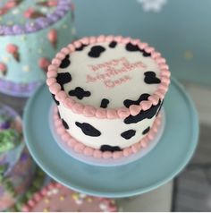 two decorated birthday cakes sitting on top of each other in front of blue and pink plates