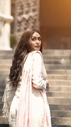 a woman with long hair walking down some steps