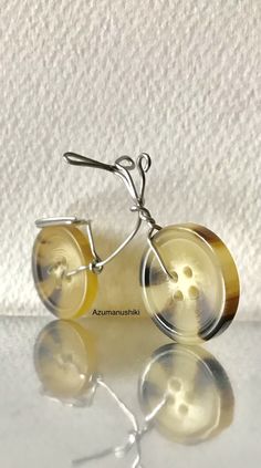 a pair of earrings that are sitting on top of a white surface with the reflection of it