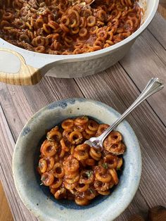 two bowls filled with pasta on top of a wooden table