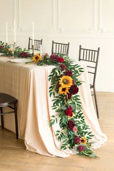 a long table with flowers and greenery on it is set up for an event