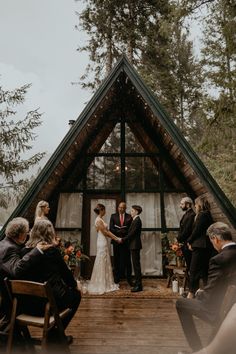 a bride and groom standing under an umbrella in front of a wedding ceremony at the lodge