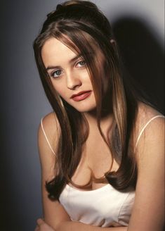 a woman with long brown hair wearing a white top