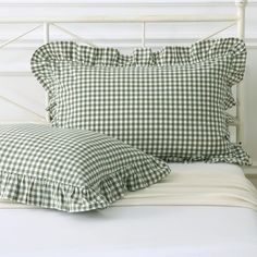 a white bed topped with green and white pillows