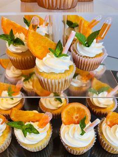 cupcakes with orange slices and garnishes on them are displayed in three different images