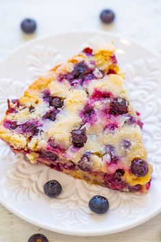 a slice of blueberry crumb cake on a white plate with fresh blueberries around it