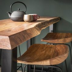 a tea kettle sitting on top of a wooden table next to two chairs and a pot