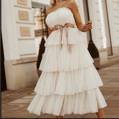 a woman in a white dress is walking down the street with her hand on her hip