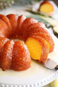 a bundt cake on a white plate with a knife in it and pineapples behind it