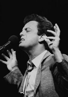 the singer performing on stage with his hands in the air and singing into a microphone