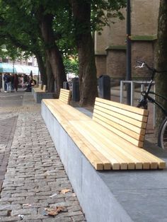 a wooden bench sitting on the side of a sidewalk