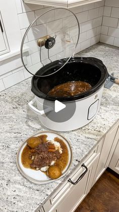 a crock pot with some food in it on a kitchen counter next to a plate