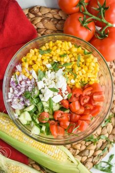 corn salad in a glass bowl with tomatoes, corn and other vegetables on the side