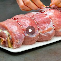 someone is cutting up raw meat on a white platter with red trimmings