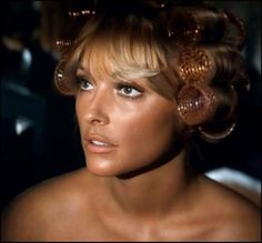 a close up of a person with very large curls on her head and wearing gold jewelry