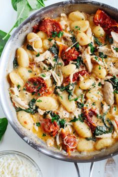 a pan filled with pasta and spinach on top of a table